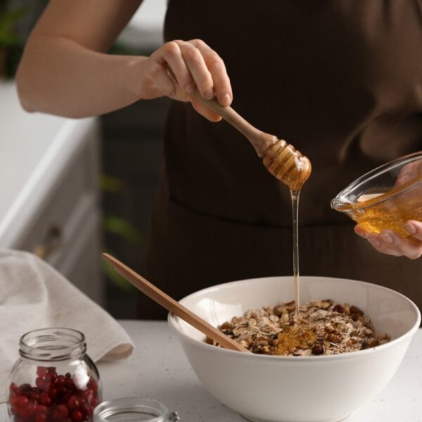 A woman adding honey to dry fruits