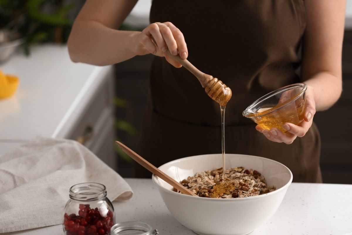 A woman adding honey to dry fruits